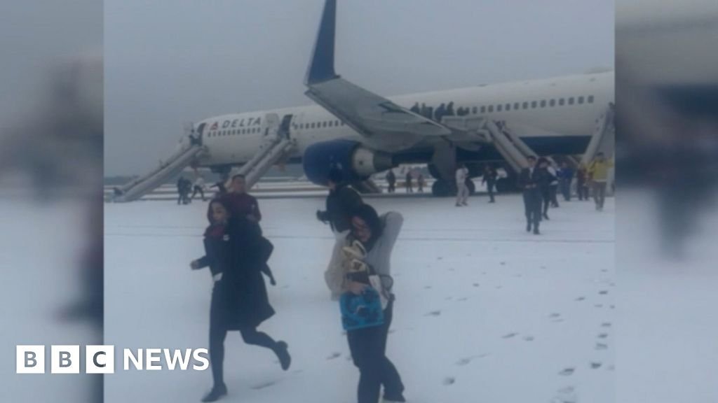 Passengers evacuate plane on snowy tarmac during storm